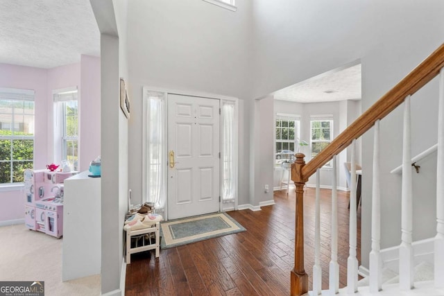 foyer entrance featuring baseboards, a textured ceiling, hardwood / wood-style floors, and stairs