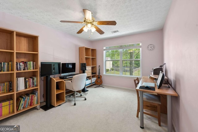 carpeted office featuring visible vents, baseboards, a ceiling fan, and a textured ceiling