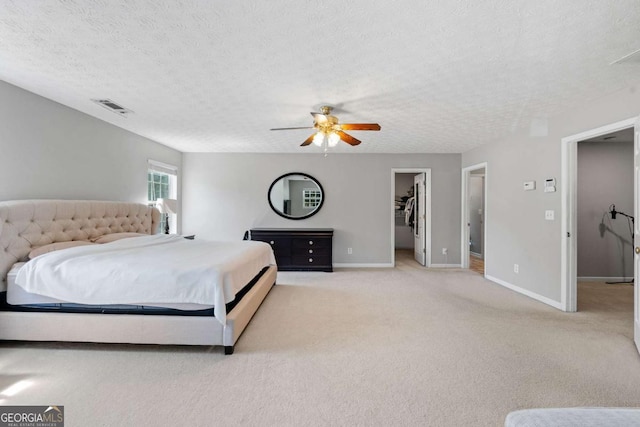 carpeted bedroom featuring a textured ceiling, baseboards, a spacious closet, and visible vents