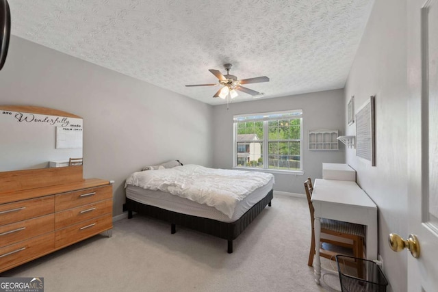 bedroom featuring ceiling fan, a textured ceiling, light colored carpet, and baseboards