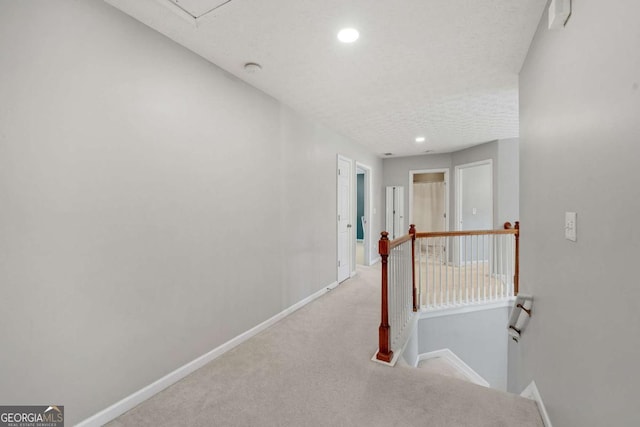 hallway with recessed lighting, baseboards, an upstairs landing, and carpet floors