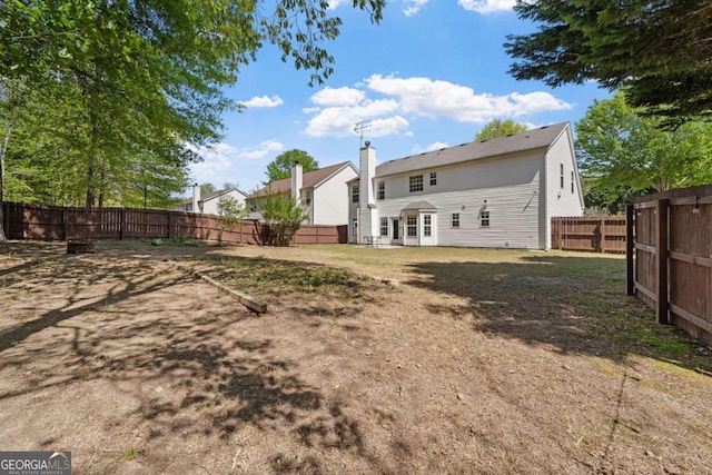rear view of house featuring a fenced backyard