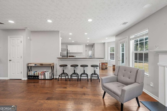 kitchen featuring white cabinetry, a peninsula, a kitchen breakfast bar, and wood finished floors