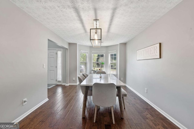 unfurnished dining area featuring dark wood-type flooring, baseboards, and a textured ceiling