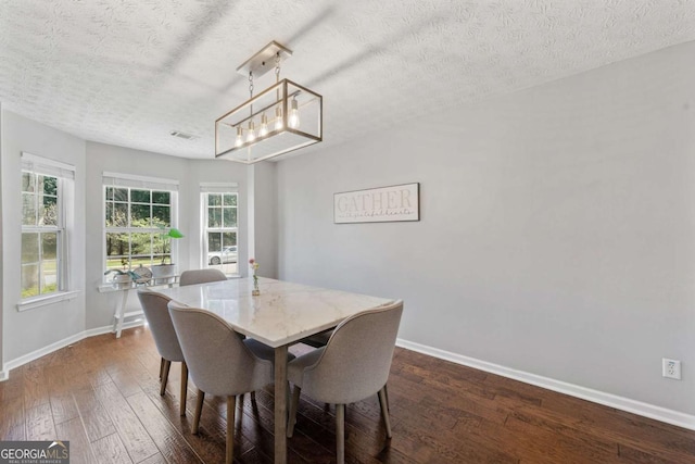 dining space with an inviting chandelier, dark wood-style floors, baseboards, and a textured ceiling