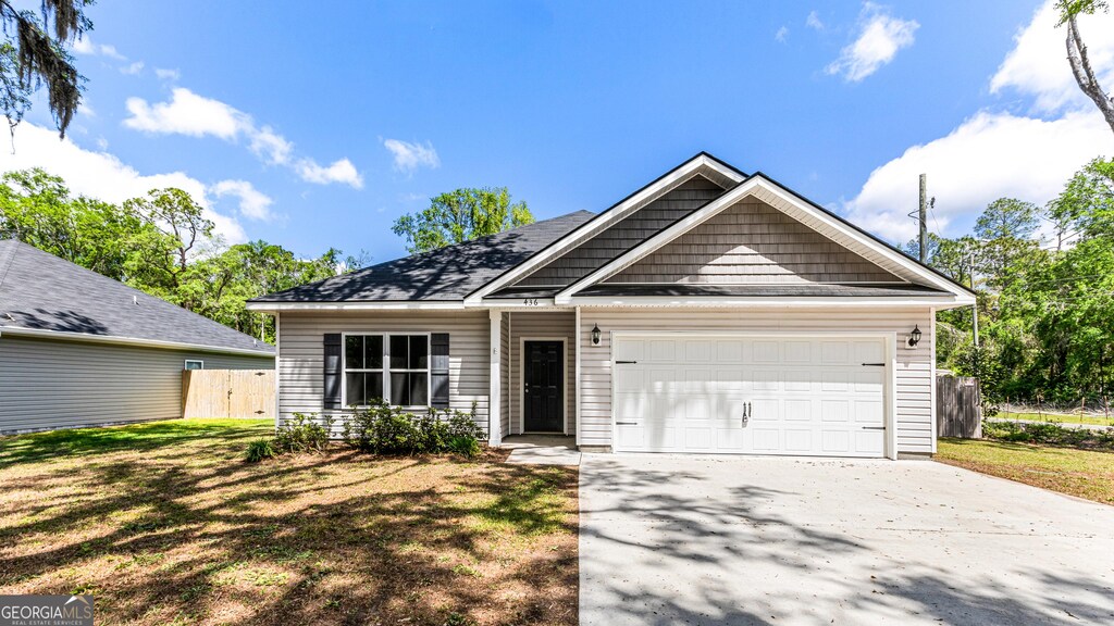 436 Talmadge Rd, Allenhurst, GA 31301 - view of front of house featuring concrete driveway, a front yard, fence, and an attached garage