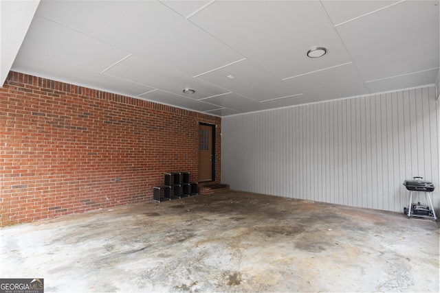unfurnished living room featuring concrete floors and brick wall
