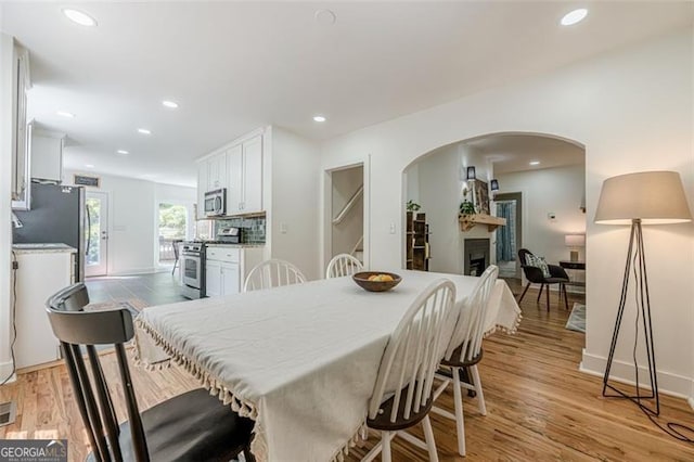 1884 Montrose Dr, East Point, GA 30344 - dining area with light wood-type flooring, arched walkways, a fireplace, baseboards, and recessed lighting