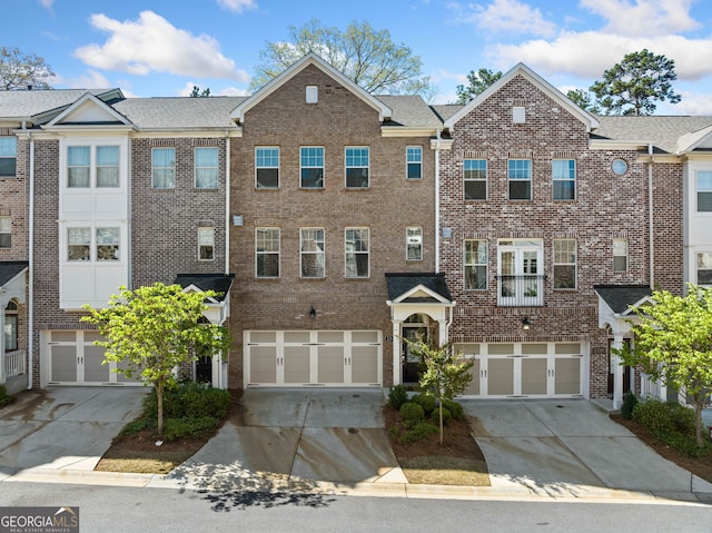 multi unit property featuring a garage, brick siding, and driveway