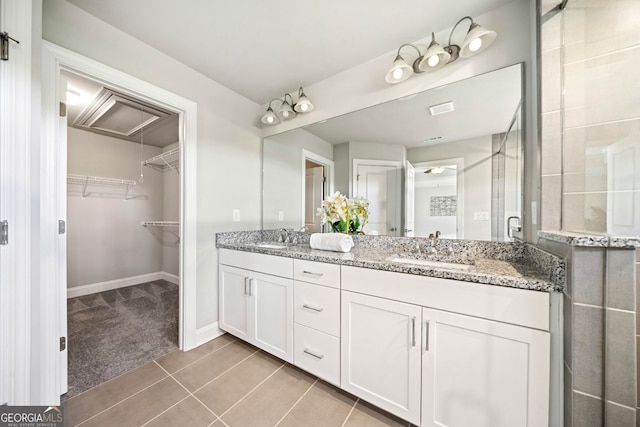 bathroom featuring a walk in closet, double vanity, a sink, and a stall shower
