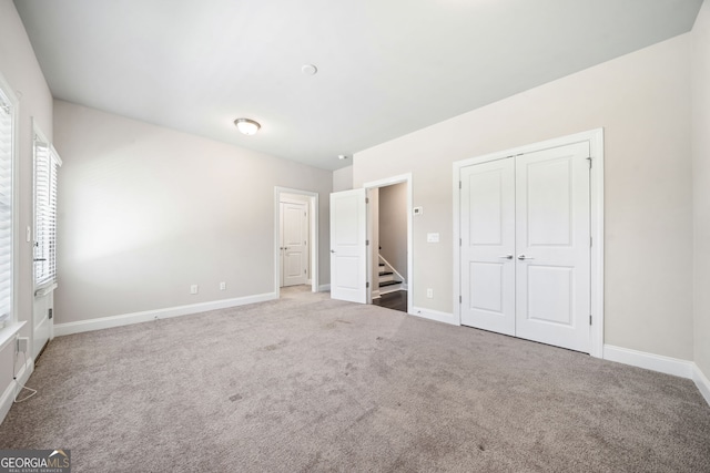 unfurnished bedroom with a closet, baseboards, and carpet