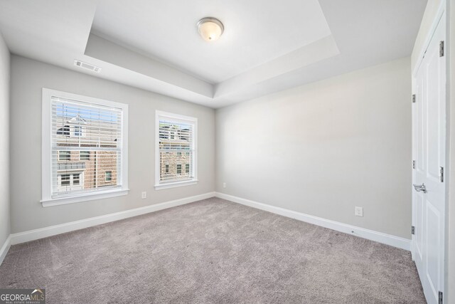 spare room featuring a raised ceiling, baseboards, and visible vents
