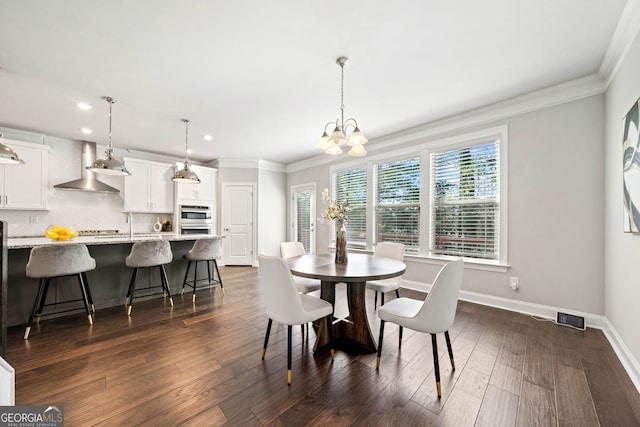 dining room with dark wood-style flooring, ornamental molding, baseboards, and a chandelier