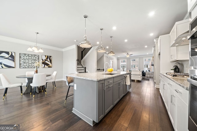 kitchen featuring dark wood-style flooring, ornamental molding, gray cabinets, a breakfast bar area, and a sink