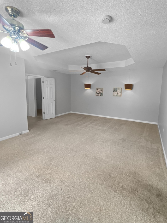 carpeted spare room with a raised ceiling, a textured ceiling, baseboards, and a ceiling fan