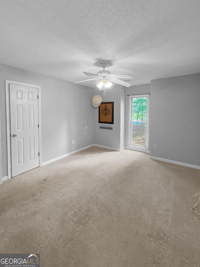 carpeted empty room with baseboards, a ceiling fan, and a textured ceiling