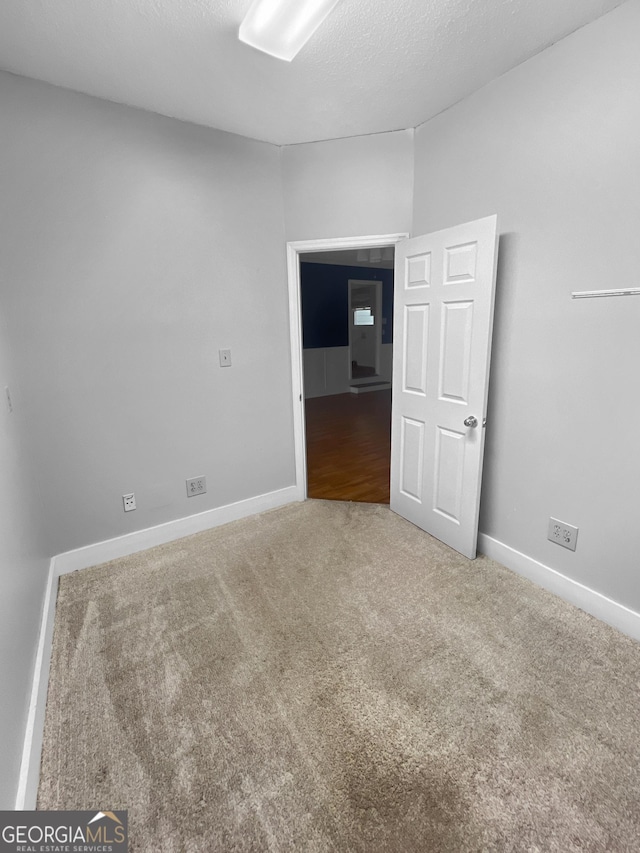carpeted spare room with baseboards and a textured ceiling