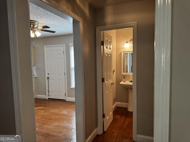 hall with baseboards, a textured ceiling, and dark wood-style floors
