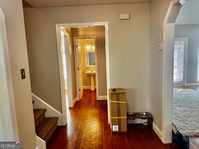 hallway with baseboards, a sink, a textured ceiling, stairs, and wood-type flooring