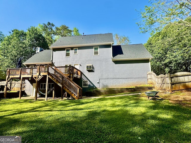 back of property featuring a wooden deck, a yard, stairway, fence, and a shingled roof