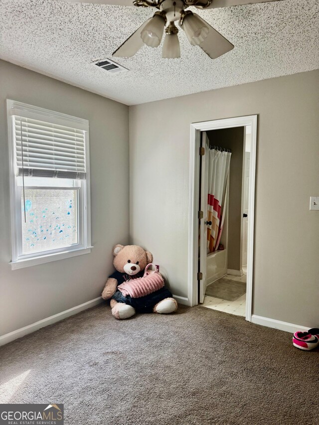interior space featuring ceiling fan, carpet flooring, baseboards, and a textured ceiling