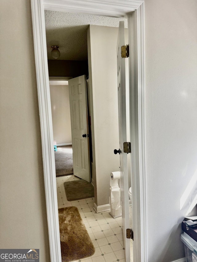 bathroom featuring toilet, baseboards, and a textured ceiling