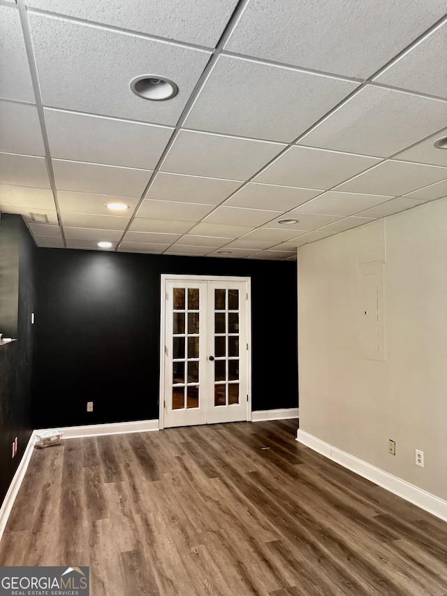 spare room with a paneled ceiling, baseboards, and wood finished floors