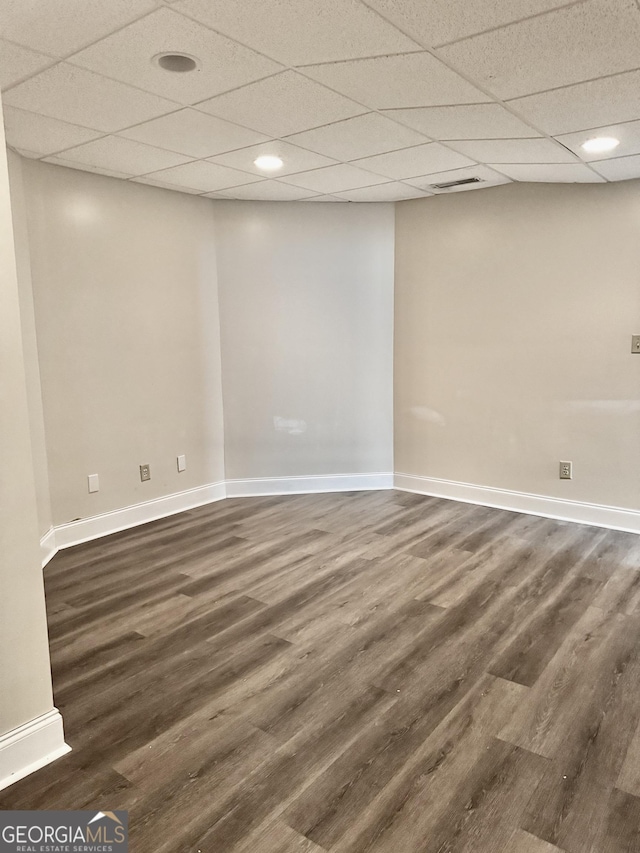 unfurnished room featuring a drop ceiling, baseboards, dark wood finished floors, and visible vents