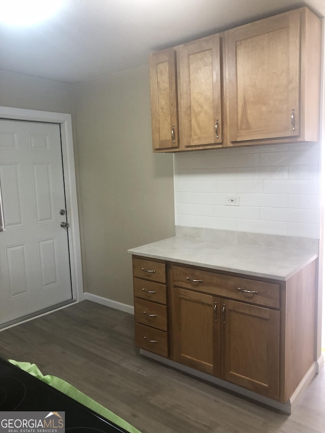 576 Pansy Ave, Macon, GA 31204 - kitchen featuring backsplash, light countertops, brown cabinets, baseboards, and dark wood-style floors