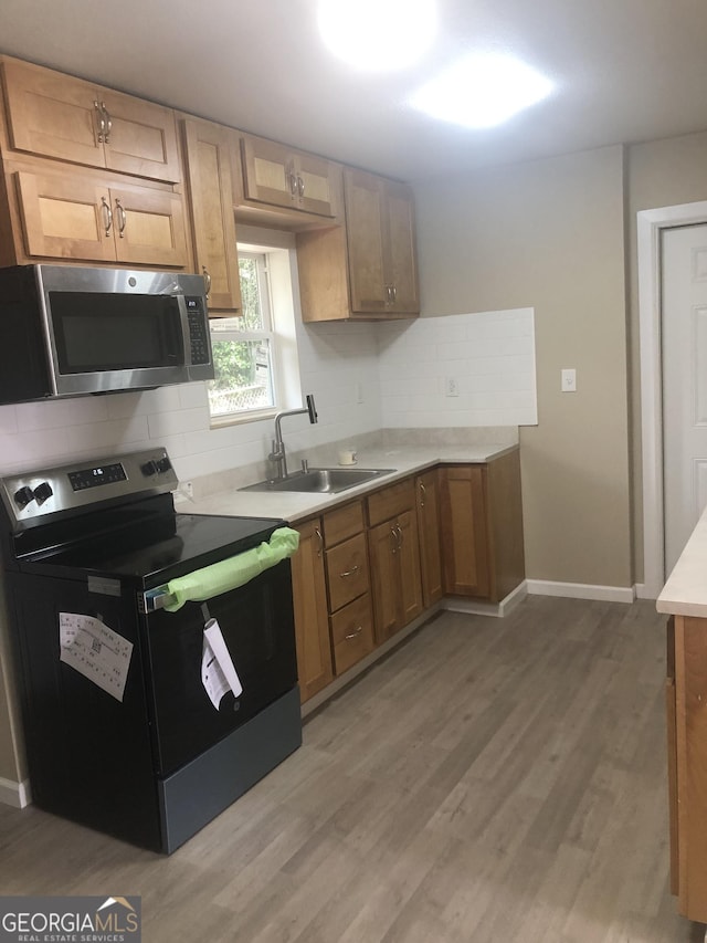 576 Pansy Ave, Macon, GA 31204 - kitchen with light wood-style floors, light countertops, a sink, stainless steel appliances, and decorative backsplash