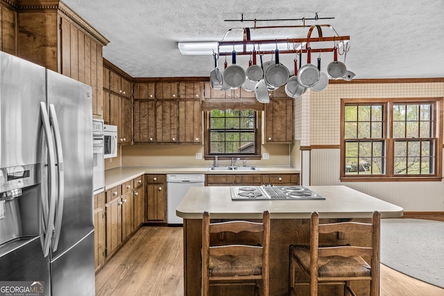 3588 SW Highridge Dr, Conyers, GA 30094 - kitchen with light wood-type flooring, a wainscoted wall, appliances with stainless steel finishes, light countertops, and wallpapered walls