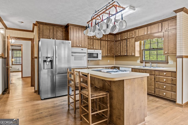 3588 SW Highridge Dr, Conyers, GA 30094 - kitchen with ornamental molding, light countertops, white appliances, a textured ceiling, and light wood finished floors