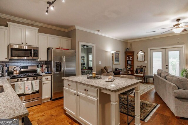 170 Elliot Cir, Watkinsville, GA 30677 - kitchen with appliances with stainless steel finishes, open floor plan, a ceiling fan, a kitchen bar, and ornamental molding