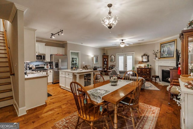 170 Elliot Cir, Watkinsville, GA 30677 - dining room featuring stairs, ornamental molding, ceiling fan, a fireplace, and light wood-style floors