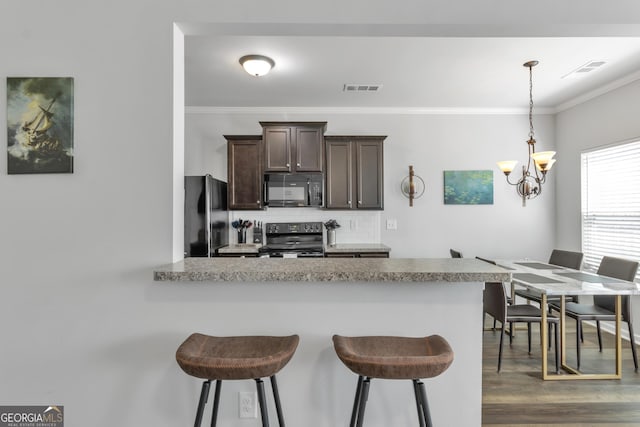 kitchen featuring a kitchen breakfast bar, backsplash, crown molding, visible vents, and black appliances