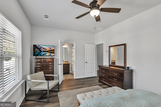 bedroom featuring baseboards, ensuite bath, a ceiling fan, visible vents, and dark wood finished floors