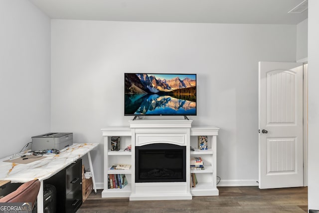 living area with a glass covered fireplace, baseboards, dark wood finished floors, and visible vents