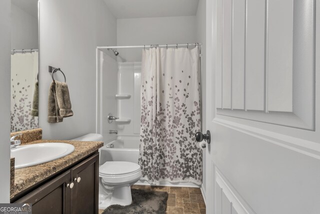 full bathroom with shower / bath combination with curtain, stone finish floor, vanity, and toilet