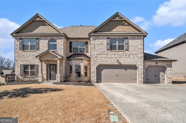 view of front of house featuring concrete driveway, a front yard, an attached garage, and brick siding