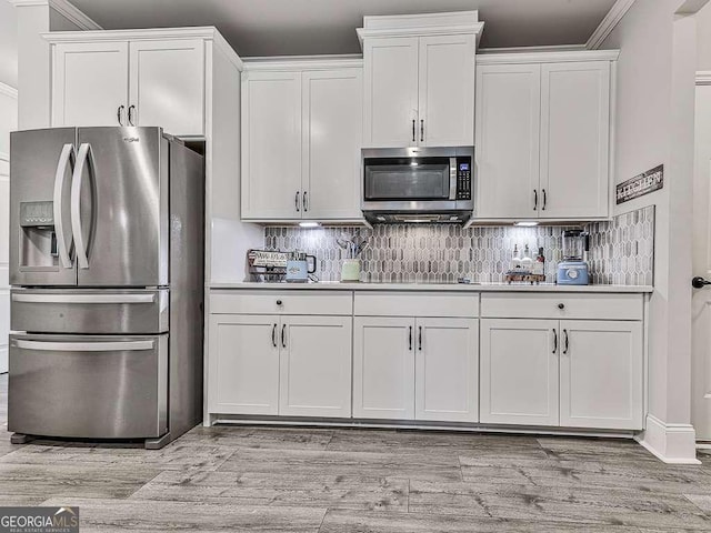 kitchen with tasteful backsplash, light wood-style floors, crown molding, white cabinetry, and stainless steel appliances