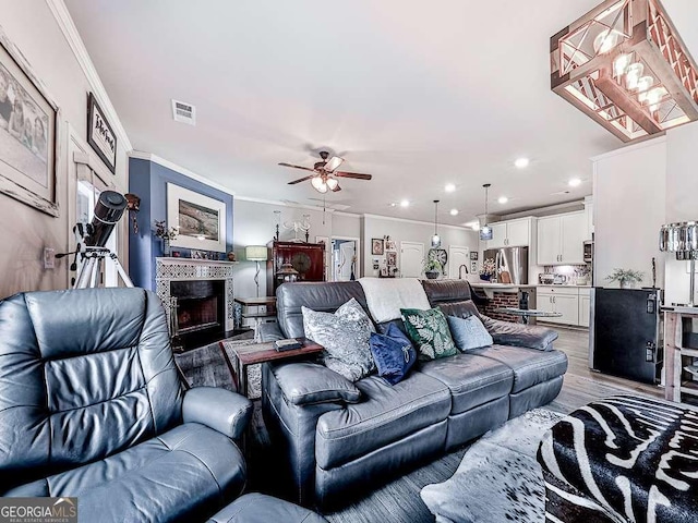 living area featuring wood finished floors, ceiling fan, ornamental molding, and recessed lighting