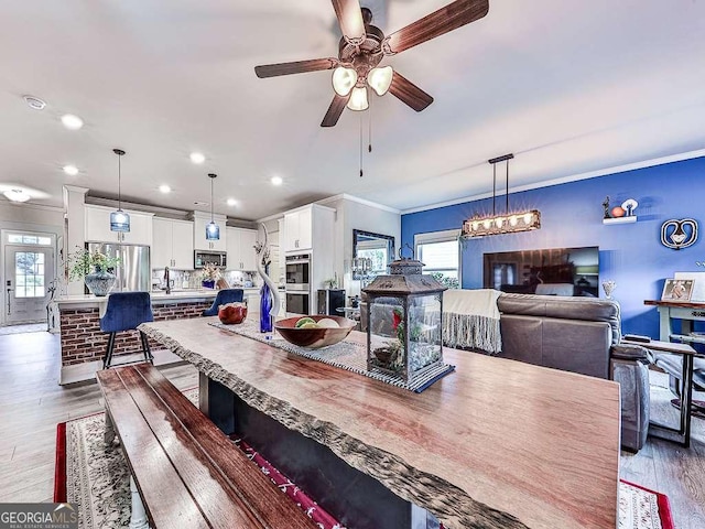 dining room featuring crown molding, a ceiling fan, plenty of natural light, and light wood-style floors