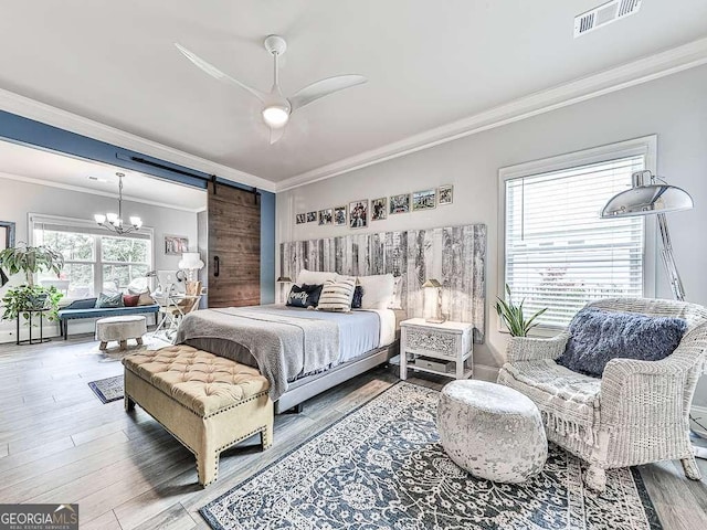 bedroom with ornamental molding, a barn door, visible vents, ceiling fan with notable chandelier, and wood finished floors