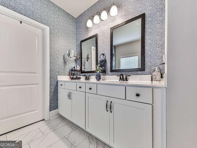 bathroom with double vanity, marble finish floor, a sink, and baseboards