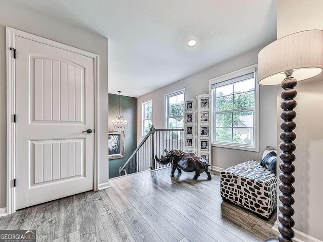 sitting room featuring a chandelier, wood finished floors, baseboards, and an upstairs landing