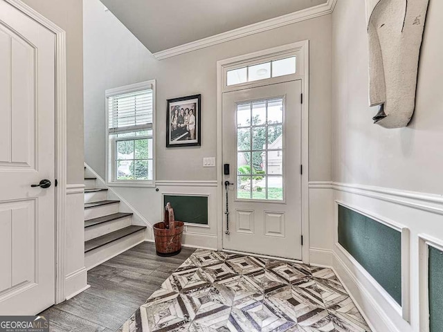entryway featuring crown molding, a wainscoted wall, wood finished floors, and stairs