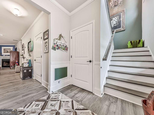 entrance foyer with baseboards, ornamental molding, a fireplace, stairs, and wood finished floors