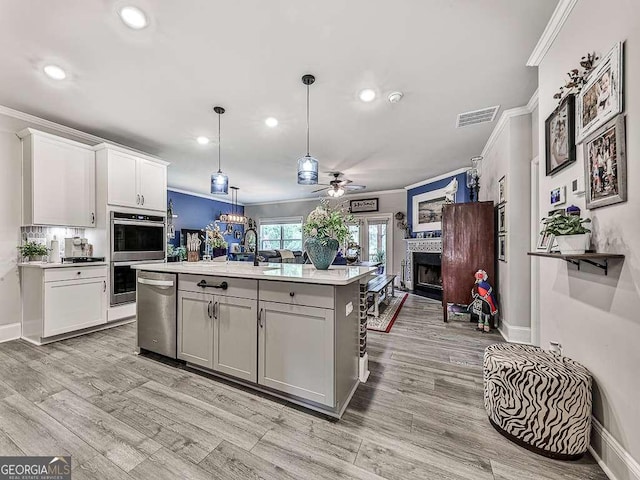 kitchen with open floor plan, light countertops, crown molding, visible vents, and ceiling fan