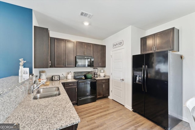 111 N Palmer St, Springfield, GA 31329 - kitchen with dark brown cabinets, visible vents, black appliances, light stone counters, and a sink