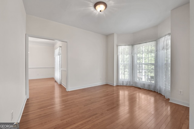 spare room with baseboards and light wood-style flooring